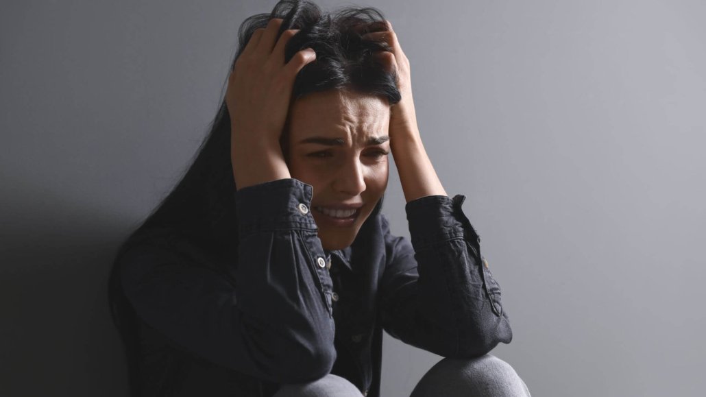 victim-mindset sad woman with head in hands representing a victim mindset